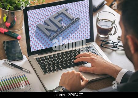 NFT nicht fungible Token blauer Text auf Laptop-Bildschirm des Computers, Büroschreibtischhintergrund. Kryptographisches Token, Blockchain-Asset, Krypto-Art-Konzept Stockfoto