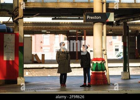 Frau und Junge mit Gesichtsmasken warten auf einen Zug am Bahnhof Preston, Lancashire, Großbritannien. Stockfoto