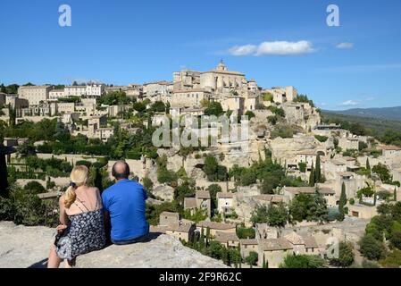 Ein paar Touristen mittleren Alters genießen die Aussicht über die Modisches Bergdorf in Gordes im Regionalpark Luberon Provence Frankreich Stockfoto