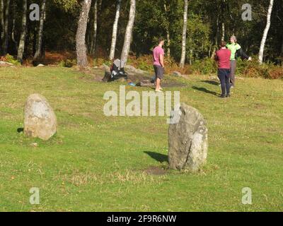 Hippie-Typen machen Yoga oder so etwas am Nine Ladies Stone Circle auf Stanton Moor in der Nähe von Matlock in Derbyshire. Stockfoto