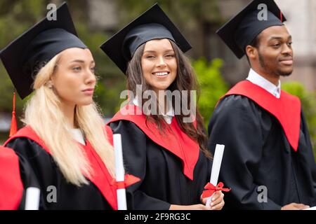 Attraktive Brünette Dame steht unter der multirassischen Gruppe von Studenten Stockfoto