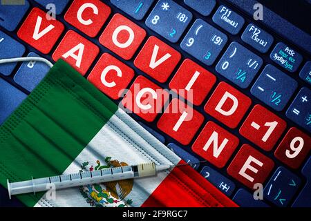 COVID-19-Immunisierung in Mexiko mit Spritze und Gesichtsmaske mit mexikanischer Flagge und Impfhinweis auf der Computertastatur. Konzept der Covid-Impfung Stockfoto