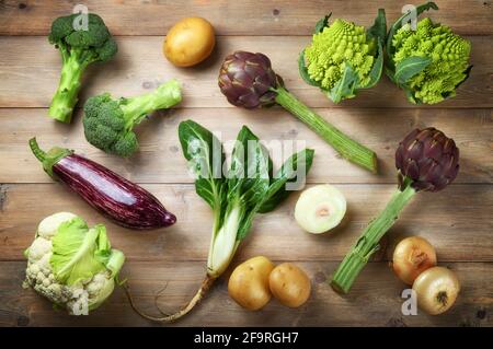 Sortiment von Bio-Gemüse auf Holzboden, flach liegend. Stockfoto
