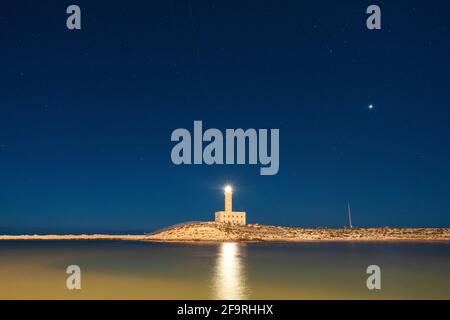 Lichtstrahl des Leuchtturms, der im Meer unter dem Sternenhimmel reflektiert wird, Vieste, Provinz Foggia, Gargano, Apulien, Italien Stockfoto