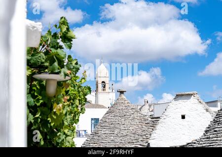 Glockenturm und konische Dächer von Trulli traditionellen Steinhäusern, Alberobello, Provinz Bari, Apulien, Italien Stockfoto