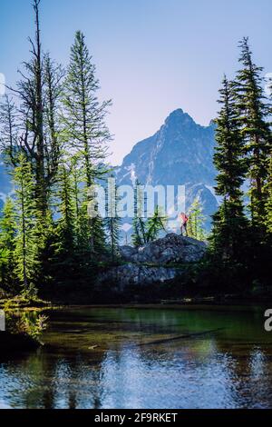 Weibliche Wanderer oben auf dem Felsen über dem alpinen See in North Cascades NP Stockfoto