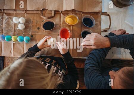 Blick von oben auf Mädchen und Vater, die ostereier färben Stockfoto