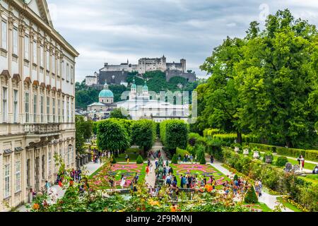 Im Hintergrund schlendern die Menschen durch den Mirabellgarten mit der alten historischen Festung Hohensalzburg in Salzburg Stockfoto