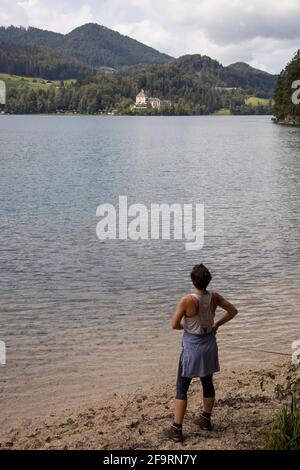 Wandererin am Fuschlsee beim Blick auf das Hotel Schloss Fuschl in Fuschl, Salzburg, Salzkammergut, Österreich, Europa. Stockfoto