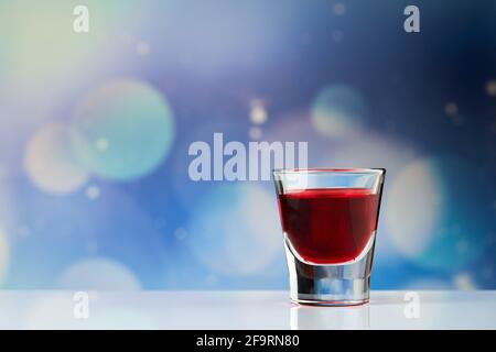 Rotes Getränk in der kleinen Aufnahme auf dem blauen Hintergrund Stockfoto