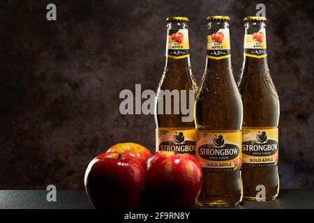 Tel-Aviv, Israel - 20.04.21.Gold Apfelwein helles alkoholisches Getränk auf dunklem Hintergrund. Drei frische rote Äpfel auf der Flaschenseite. Stockfoto