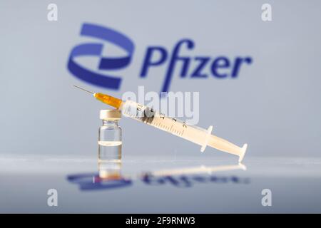 Pfizer Coronavirus-Impffläschchen und Spritze mit Logo als Hintergrund. LJUBLJANA, SLOWENIEN: 25. März 2021 Stockfoto