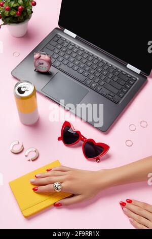 Kreative Komposition mit Frauenhänden, Planer Ende Accessoires über rosa Tisch. Weibliche Frühling Sommer Mode. Stockfoto