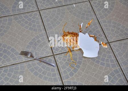 Abgefallener Teller mit Pasta auf dem Küchenboden Stockfoto