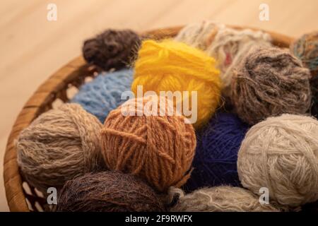 Strickmaterial aus nächster Nähe. Kugeln aus Strickwolle in einem runden Korbkorb. Stockfoto