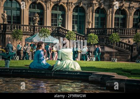 17. Mai 2019 Dresden, Deutschland - zwei Frauen im barocco-Stil mit ausgefallenen Schirmen sitzen während des Kostümfestes in der Nähe des Zwinger-Brunnens Stockfoto