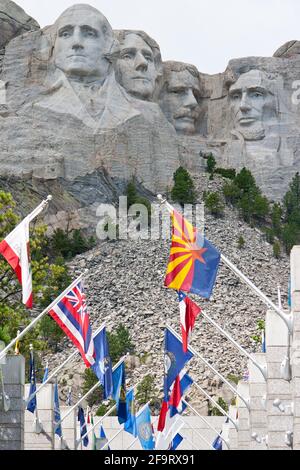 Vertikale Aufnahme des Mount Rushmore mit den geformten Köpfen von US-Präsidenten durch Flaggen gesehen Stockfoto