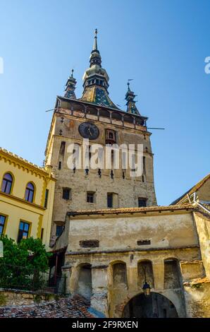 Uhrturm einseitig durch alte Gebäude innen mittelalterliche Stadt von Sighisoara/Schäßburg, Siebenbürgen, Rumänien Stockfoto