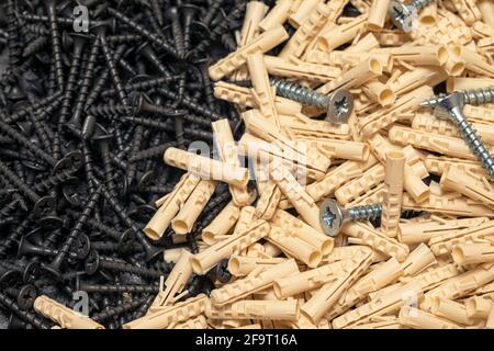 Eine Handvoll Nylondübel für selbstschneidende Schrauben und Holzschrauben. Abstraktion der Konstruktion. Industrieller Hintergrund. Stockfoto