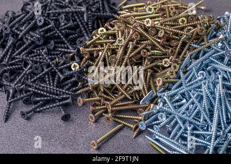 Eine Handvoll selbstschneidende Schrauben aus Stahl. Abstraktion der Konstruktion. Industrieller Hintergrund. Stockfoto