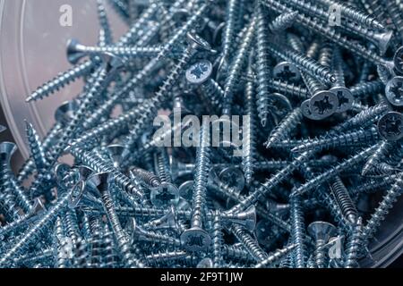 Eine Handvoll selbstschneidende Schrauben aus Stahl. Abstraktion der Konstruktion. Industrieller Hintergrund. Stockfoto