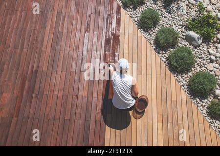 Ölauftrag von Holzdecks, Ansicht von oben über die Person, die die Terrasse einölt, Oberflächenöl von Deck oder Holzschliff Stockfoto