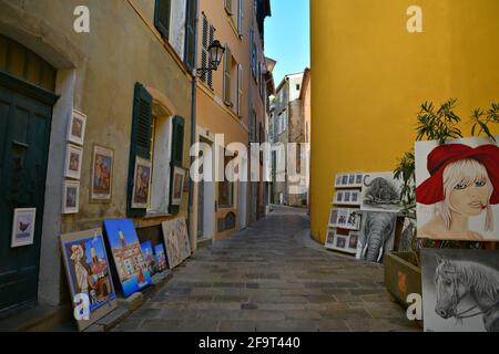 Kunstgalerie auf beiden Seiten einer gepflasterten Gasse im historischen Zentrum von Saint-Tropez an der französischen Riviera. Stockfoto