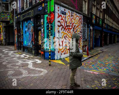 Ein Mann mit Kapuze an der Ecke einer malerischen Straße in Amsterdam. Stockfoto