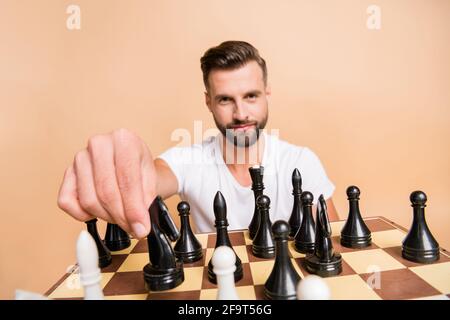 Porträt von netten Inhalt Kerl spielen Schach machen bewegen Pferd Figur isoliert auf beigefarbenem pastellfarbenem Hintergrund Stockfoto