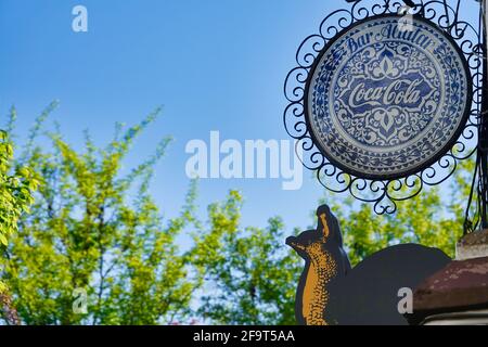 Granada, Spanien; 18. April 2021: Altes, rundes Coca-Cola-Logo in Blau und Weiß, das auf einer Straße in Granada (Spanien) für ein Restaurant steht Stockfoto