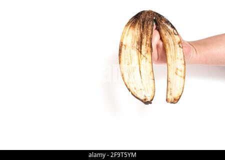 Hand hält braune Schale von Banane isoalted auf einem weißen mit Kopierraum. Stockfoto