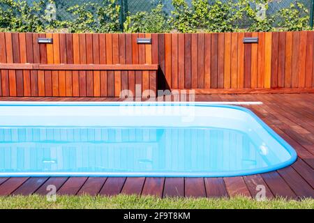 Swimmingpool mit Ipe-Holzterrasse und grünem Gras. Exotisches Hartholz, Ipe-Terrasse neben dem Swimmingpool aus nächster Nähe Stockfoto