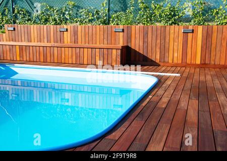 IPE Holzterrasse und Swimmingpool. Hinterhof-Terrasse am Pool, blaues Wasser im Kontrast zu tropischen Hartholzbrettern und wunderschöner Holzstruktur Stockfoto