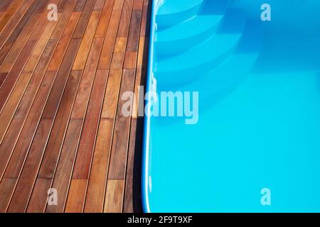 IPE Holzterrasse und Swimmingpool aus nächster Nähe. Gartenterrasse am Pool, blaues Wasser im Kontrast zu tropischen Hartholzplatten. Stockfoto