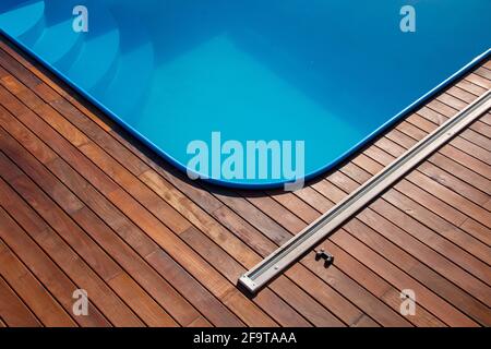 IPE Holzterrasse und Swimmingpool. Terrassendesign am Pool, blaues Wasser im Kontrast zu exotischen Hartholzbrettern und wunderschöner Holzstruktur. Stockfoto