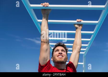 Fitness Monkey Bars Mann Training Arme Muskeln im Dschungel Fitnessstudio im Freien im Sommer. Athlet trainieren Greifen Klettern auf Leiter Ausrüstung beim Sport Stockfoto