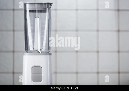 Leeren Sie den elektrischen Mixer in der Küche für Cocktails und gesunde Lebensmittel. Weißer Mixer auf dem Tisch mit hellen Küchenfliesen. Minimales Konzept, Kopierspeicher Stockfoto