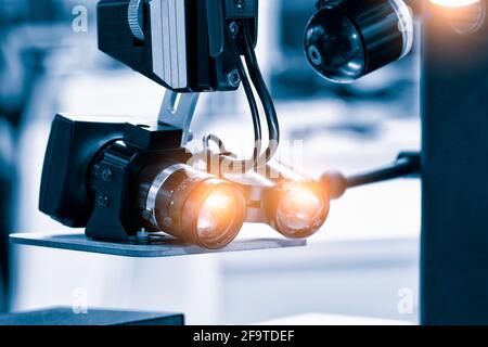 Nahaufnahme eines Metalloptiklinsenobjektivs, weißes optisches Mikroskop für sterile Aufnahmen im Operationsraum. Medizinische Wissenschaft Biologie Gerät Technol Stockfoto