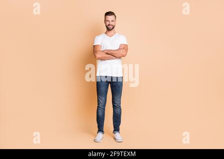 In voller Länge Foto von jungen schönen Mann glücklich positive Lächeln Selbstbewusst gekreuzte Hände isoliert auf beigefarbenem Hintergrund Stockfoto