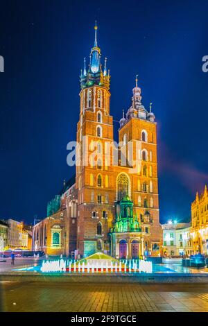 Nachtansicht der Marienkirche mit der Statue von adam mickiewicz auf dem rynek glowny Hauptplatz in der polnischen Stadt Krakau. Stockfoto