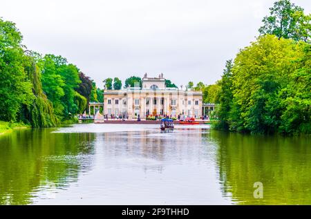 Ein Boot nähert sich dem Palast auf dem Wasser, auch Lazienki Palast oder Palast auf der Insel im Lazienki Royal Park, Warschau, Polen genannt Stockfoto