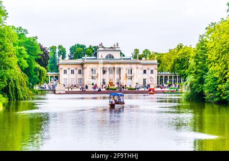 Ein Boot nähert sich dem Palast auf dem Wasser, auch Lazienki Palast oder Palast auf der Insel im Lazienki Royal Park, Warschau, Polen genannt Stockfoto