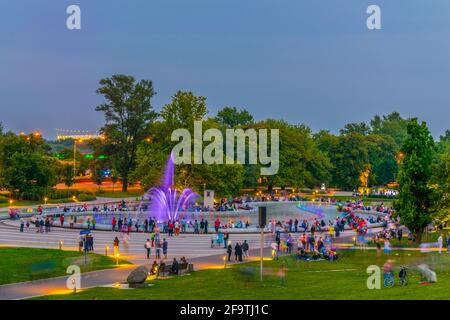 Um den Multimedia Fountain Park versammeln sich Menschen, um die beleuchteten Brunnen in Warschau, Polen, zu sehen. Stockfoto