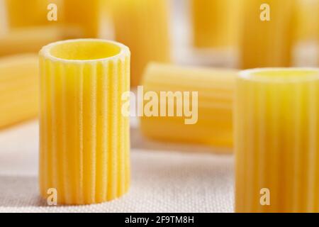 Italienische Pasta genannt Mezzi rigatoni auf weißem Baumwolltuch, röhrenförmig Pasta mit Rippen in ihrer Länge, Studioaufnahme Stockfoto