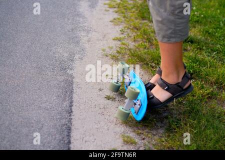 Unschärfe kleinen Jungen macht Tricks auf einem Penny Skateboard. Kleines Kind, das auf einem Skateboard im Park reitet. Das Kind lernt, mit einem Blue Penny Board zu fahren und zu tun Stockfoto