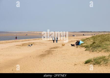 Menschen, die Hunde am Strand von Hunstanton, Norfolk, England, laufen. Stockfoto