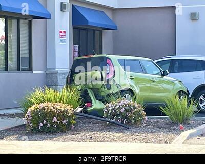 FRESNO, VEREINIGTE STAATEN - 13. Apr 2021: Ein Foto eines kleinen grünen viertürigen Autos bei einem Unfall und dem hinteren Ende summierte sich und landete in der Nähe des Bürogebäudes Stockfoto