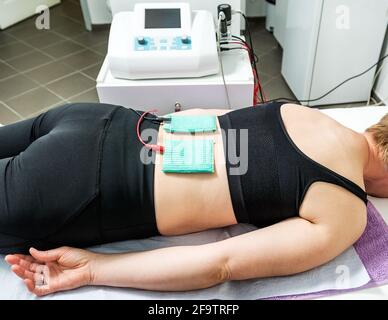 Elektrostimulation in der Physiotherapie bei einer weiblichen Patientin. Ärztlicher Check im Rücken in einem Physiotherapie-Zentrum. Stockfoto