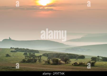 Eastbourne, East Sussex, Großbritannien. April 2021. Nach einem strahlend warmen, sonnigen Tag zieht dichter Meeresnebel ein. Ziemlich spektakuläre Aussichten von höher oben in der Nähe von Beachy Head mit Blick nach Westen über die nebelgefüllten Täler. Der Leuchtturm Belle Tout links im Bild. Kredit: David Burr/Alamy Live Nachrichten Stockfoto