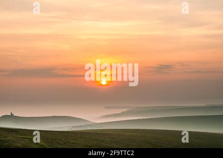 Eastbourne, East Sussex, Großbritannien. April 2021. Nach einem strahlend warmen, sonnigen Tag zieht dichter Meeresnebel ein. Ziemlich spektakuläre Aussichten von höher oben in der Nähe von Beachy Head mit Blick nach Westen über die nebelgefüllten Täler. Der Leuchtturm Belle Tout links im Bild. Kredit: David Burr/Alamy Live Nachrichten Stockfoto